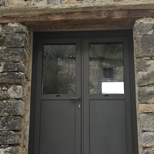 Porte d’entrée en aluminium, 2 vantaux, de couleur gris 2900 sablé, avec panneaux pleins en partie basse et vitrages en partie haute (vue extérieure)