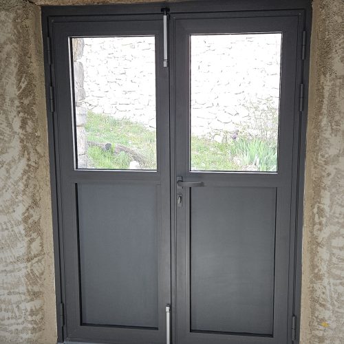 Porte d’entrée en aluminium, 2 vantaux, de couleur gris 2900 sablé, avec panneaux pleins en partie basse et vitrages en partie haute (vue intérieure)